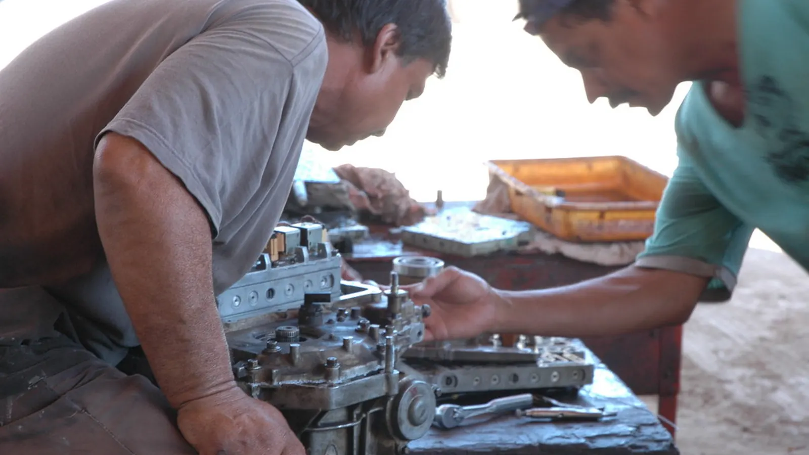 Two mechanics repairing a vehicle engine
